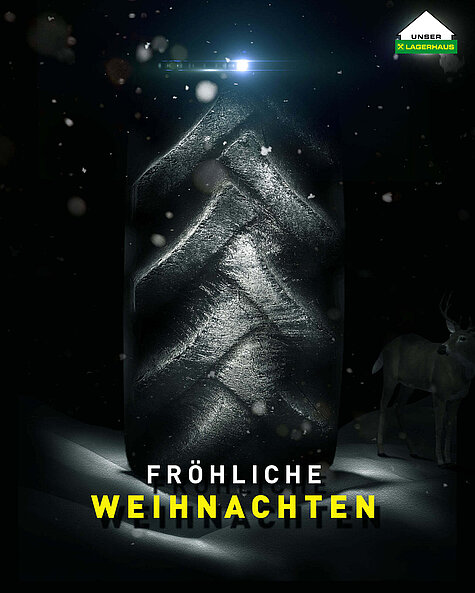 Nahaufnahme eines großen Reifens im Schnee mit Lichteffekten, umgeben von fallendem Schnee. Ein Hirsch steht im Hintergrund. Text "Fröhliche Weihnachten" und Lagerhaus-Logo oben rechts.