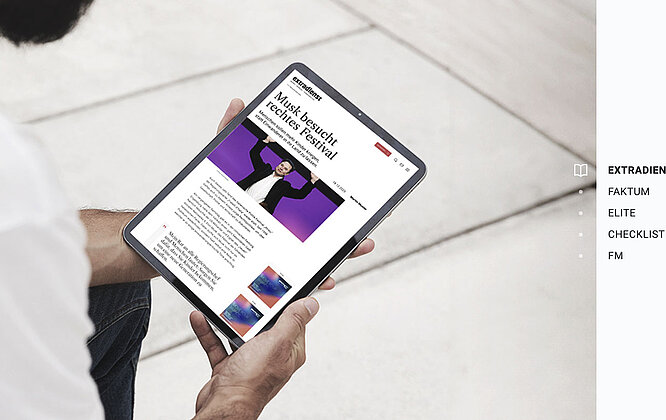 Mann mit Tablet, auf dem die Startseite des extradienst zu sehen ist.